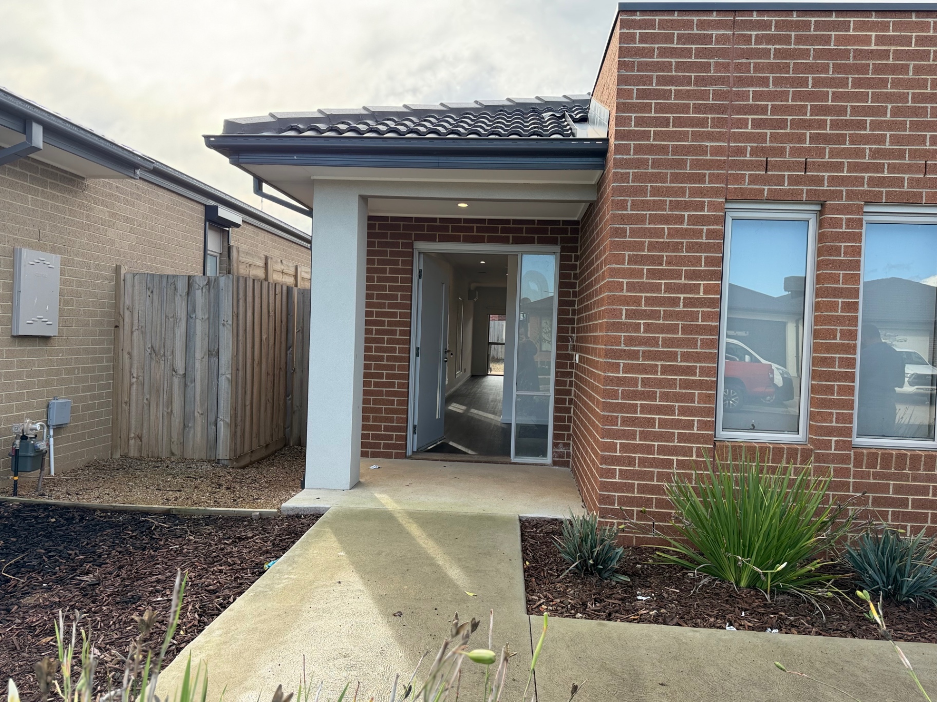 Welcoming covered entry with wide pathway leading to the front door