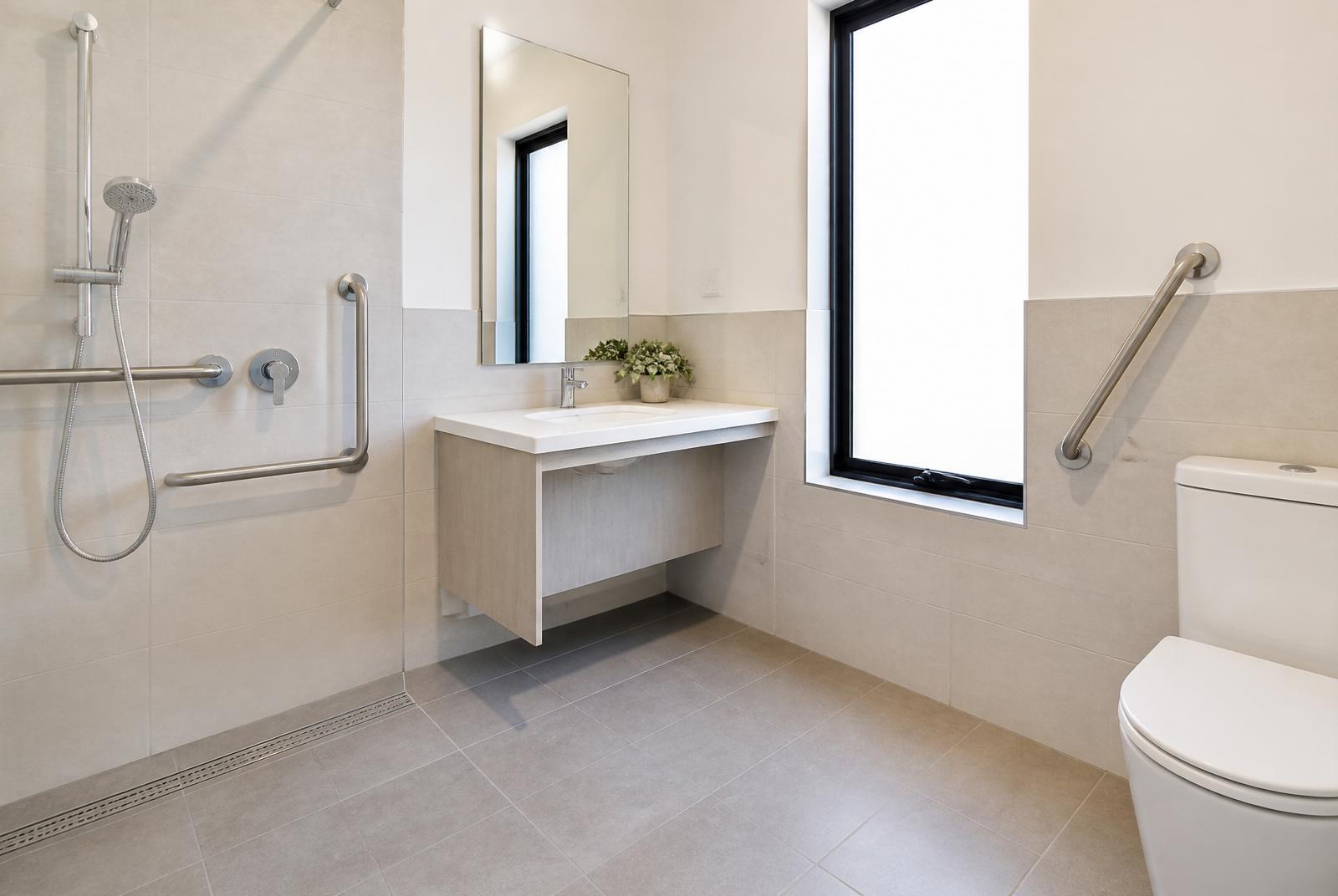 Accessible bathroom with roll-in shower, grab rails and wall-hung vanity